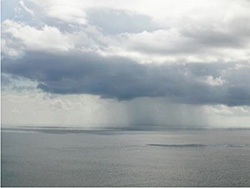 rain falling from a cloud over the ocean